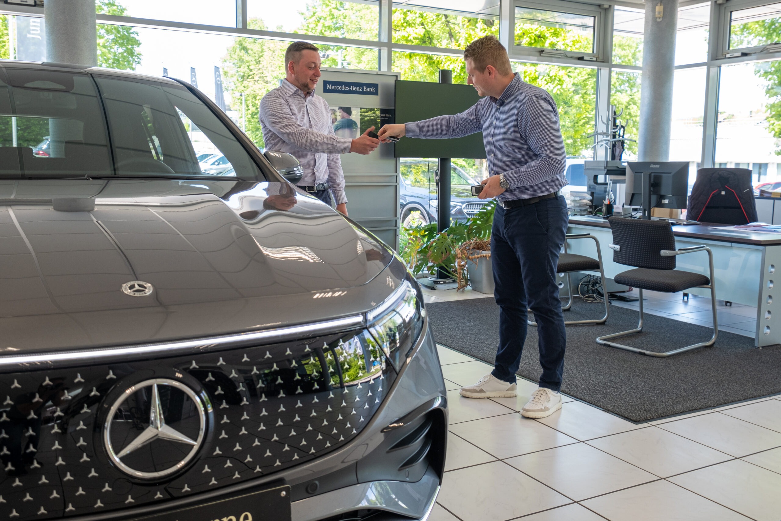 chlüsselübergabe im Autohaus Franz Schmid – Mitarbeitender übergibt Fahrzeugschlüssel an Kundin/Kunden
