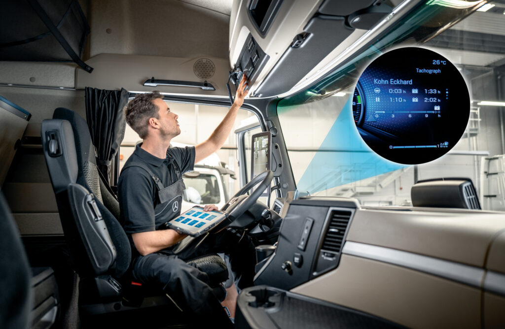 Werkstattmitarbeiter im Fahrerhaus eines Mercedes-Benz Lkw bei der Nachrüstung und Kalibrierung eines digitalen Tachographen.